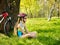 Bikes cycling girl wearing helmet have a rest sitting under tree.