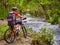 Bikes girl with big rucksack cycling fording throught water .