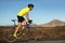 Biking cyclist male athlete going uphill on open road training hard on bicycle outdoors at sunset