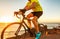 Biking cyclist riding road bike with smartwatch athlete training at sunset outdoor cycling. Sport smart watch fitness