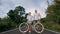 Biking road trip. Love couple on blue bike in white clothes on forest road. Just married woman and man kiss, hugs, stand