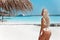 Bikini Model enjoying on tropical beach. Pretty slim girl posing on exotic island in turquoise ocean. Blonde in trendy swimwear