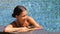 Bikini woman lying relaxing in infinity pool