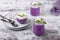 Bilberry mousse topped with whipped cream and mint in glass jars