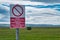 A bilingual sign in English and Welsh warns the public to keep out of land designated for use as a military firing range