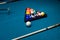 Billiard cue and colour balls on snooker table while game