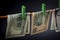 Bills, dollars are fixed on the rope with green clothespins, background