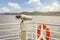 Binocular tourism telescope on the deck of a ferry ship with a lifeline buoy.