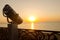 Binoculars on the coast of the sea. Tourist telescope on a background of sunset on the waterfront. Summer