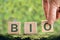 BIO - tex word on a wooden cube in the forest on a green background. bio concept, symbol of balance in nature living