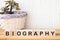 BIOGRAPHY word concept written on wooden blocks, cubes on a dark table with flower and a light background
