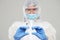 Biological hazard. Epidemic of the Chinese coronavirus. An asian woman in a protective suit and mask holds an injection syringe an