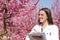 Biologist checking flowers of pink peach trees