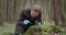 Biologist in rubber gloves examining moss at forest