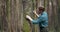Biologist studying plants with magnifying glass at forest