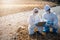 Biologist wear protective suit and mask collects sample of waste water from industry