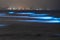 Bioluminescent tide glows in Del Mar, California. Urban lights in the background.