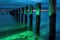 bioluminescent waves gently lapping at a piers pilings