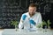 A biotechnologist in a modern laboratory conducts experiments with synthesizing compounds using droppers and plants in a