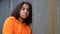 Biracial African American girl teenager young woman looking sad wearing an orange hoodie in an urban city environment