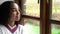 Biracial African American girl teenager young woman wearing a white jumper sitting looking out of a window looking sad then happy