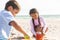 Biracial boy and girl playing while making sandcastle with toys at beach on sunny day