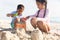 Biracial brother and sister using toys for making sandcastle at beach on sunny day