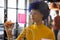 Biracial casual businesswoman with blue afro making notes on glass wall in office