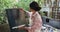 Biracial female artist in apron painting on canvas in sunny garden, slow motion