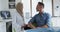 Biracial female dentist talking with male patient at modern dental clinic