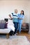 Biracial female physiotherapist assisting caucasian senior man with backache in standing at home