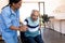 Biracial female physiotherapist assisting smiling caucasian senior man in getting up from wheelchair