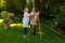 Biracial happy senior woman painting with husband on canvas while standing against plants in yard