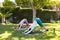 Biracial lesbian couple practicing yoga dog pose in sunny garden, copy space