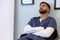 Biracial male doctor taking nap in hospital waiting room