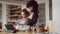 Biracial mother and daughter in modern-styled kitchen sifting flour in bowl to bake a cake.