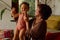 Biracial mother and daughter smiling while playing in living room at home