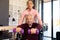 Biracial physiotherapist assisting caucasian senior man sitting on wheelchair in lifting dumbbells