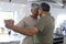 Biracial senior couple with head to head holding hands and dancing in kitchen