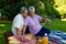 Biracial senior woman taking selfie with husband over mobile phone while sitting on blanket in park