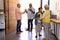 Biracial seniors receiving friends with bouquet and champagne bottle in nursing home, copy space