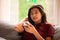 Biracial teen girl sitting on gray couch looking at smartphone
