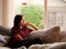 Biracial teen girl sitting on gray couch by window, thinking