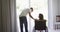 Biracial woman in wheelchair and smiling male partner talking and looking out of living room window