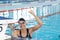 Biracial young female swimmer celebrating indoors in pool, wearing goggles