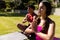 Biracial young woman with boyfriend practicing meditation in prayer pose while sitting in yard