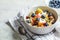 Bircher muesli or overnight oatmeal with apple, banana and blueberries in gray bowl