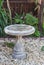 Bird bath outside on rock gravel in designed garden