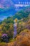 Bird eye view of asphalt pathway in autumn mixed and deciduous forrest with dam at the top of river tranquility landscape