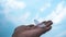 Bird feather in a hand in abstract groups of stratus clouds height in the sky